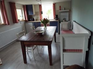 a small kitchen with a wooden table and chairs at Wad'n Dream in Moddergat