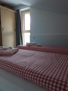 2 camas en una habitación con una manta a cuadros roja y blanca en DAV-Haus (Alpenverein), en Obertauern