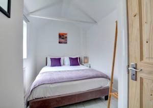 The Pearl - Stylish 3 Bedrooms house in great central location في برايتون أند هوف: غرفة نوم مع سرير مع وسائد أرجوانية