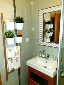 La salle de bains est pourvue d'un lavabo, d'un miroir et de plantes. dans l'établissement SunHouse Room, à Albufeira