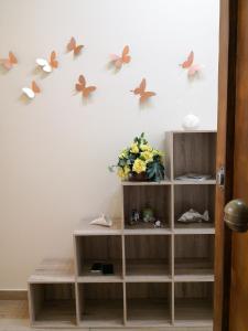 a shelf with butterflies on a wall with a vase of flowers at Corso Italia 83 in Taranto