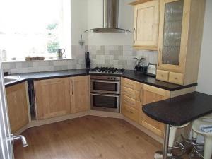 a kitchen with wooden cabinets and a stove top oven at Kirkmay House in Crail