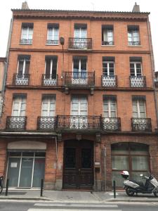 un edificio de ladrillo rojo con una moto aparcada delante de él en Capitole Jeanne d Arc - Nice comfortable flat, central, balcony and charm, en Toulouse