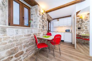a kitchen and dining room with red chairs and a stone wall at First Vestibul in Split