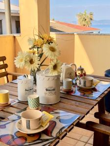 stół z kubkami, talerzami i kwiatami na balkonie w obiekcie Appartamento Francesca w mieście Alghero