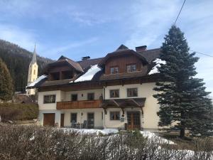 dom ze śniegiem na dachu i kościół w obiekcie Gästehaus Wastian w mieście Weissbriach