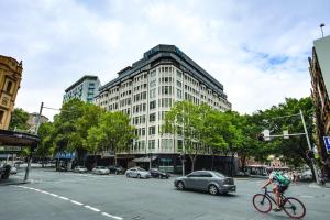 una persona montando una bicicleta en una calle con un edificio en Vibe Hotel Sydney, en Sídney