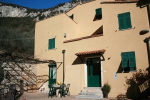 a large yellow building with green shutters and a table at Agriturismo Alveare in Finale Ligure