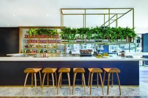 a bar with four stools in front of a counter at Vibe Hotel Sydney in Sydney