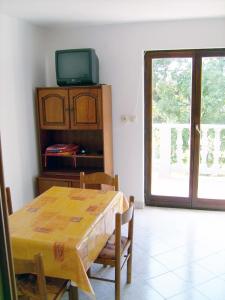 a dining room with a wooden table and a television at Apartment in Lopar/Insel Rab 17747 in Lopar