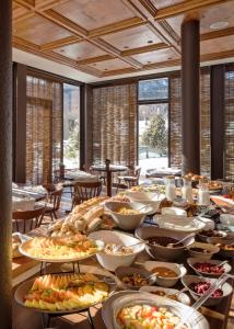 a table filled with lots of plates of food at Faloria Mountain Spa Resort in Cortina dʼAmpezzo