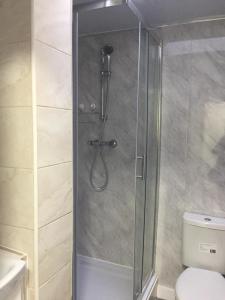 a shower with a glass door next to a toilet at Sama's Stylish Hotel Room 4 in Manchester