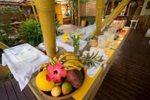 a table with a bowl of bananas and fruit on it at Pousada Treze Luas in Ilha do Mel