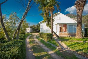 a white house with palm trees on a dirt road at Holiday Home Nives in Tivat