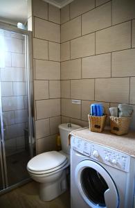 łazienka z toaletą i pralką w obiekcie Marina Apartment w mieście Artemida