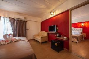 a hotel room with a bedroom with red walls at Infinite Hotel in Bangkok