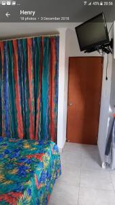 1 dormitorio con 1 cama y TV de pantalla plana en Tropical Studio Apartment, en Palm-Eagle Beach