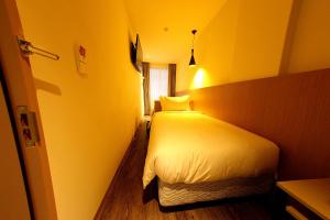 a bedroom with a white bed in a yellow room at 26 Inn in Yilan City