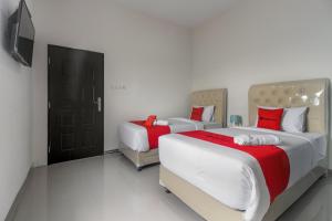 a bedroom with two beds and a television in it at RedDoorz near Mall SKA Pekanbaru in Pekanbaru