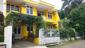 ein gelbes Haus mit einem weißen Tor davor in der Unterkunft Cendana Mulia Hostel Bogor in Bogor