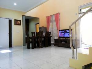 sala de estar con TV y mesa con sillas en Cendana Mulia Hostel Bogor, en Bogor