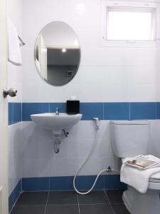 a bathroom with a sink and a toilet and a mirror at โรงแรม เดอะริช ราชพฤกษ์ โฮเทล แอนด์ เรสซิเดนซ์ in Nonthaburi