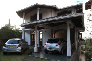 two cars parked in front of a house at Arcadia House Hanthana in Kandy