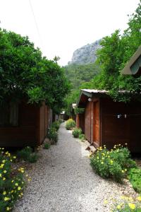 um caminho de cascalho entre dois edifícios com árvores e flores em Olympos Doga Pansiyon em Olympos