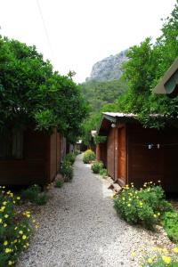 a gravel path between two buildings with trees and flowers at Olympos Doga Pansiyon in Olympos