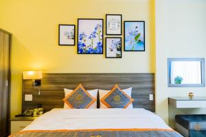 um quarto com uma cama com quatro fotografias na parede em VF Hotel Dalat em Da Lat