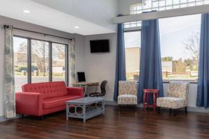 a living room with a red couch and two chairs at Microtel Inn by Wyndham Lake Norman in Cornelius