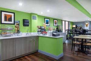 a restaurant with green walls and a table and chairs at Microtel Inn by Wyndham Lake Norman in Cornelius