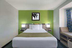 Un dormitorio con una cama grande y una pared verde en Microtel Inn by Wyndham Lake Norman, en Cornelius