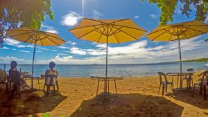 grupa ludzi siedzących na plaży z parasolami w obiekcie RedDoorz Plus @ Gracey Dive Resort Dumaguete w mieście Dauin