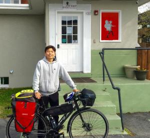 un hombre parado junto a una bicicleta delante de una casa en Base Camp Anchorage Hostel en Anchorage