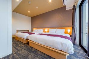 two beds in a room with a large window at RESI STAY Gojozaka in Kyoto
