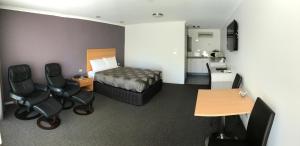 Sportsmans Motor Inn في Barooga: غرفه فندقيه بسرير ومكتب وكراسي