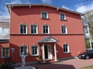 a red house with a car parked in front of it at Apartments Villa Seeblick in Baabe