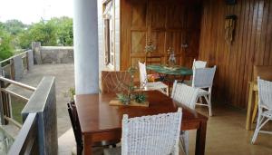 a porch with a wooden table and white chairs at Chez Clenya Guesthouse in Rodrigues Island