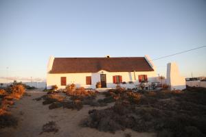 a small white house with a brown roof at Fisherman's Cottage in Hondeklipbaai