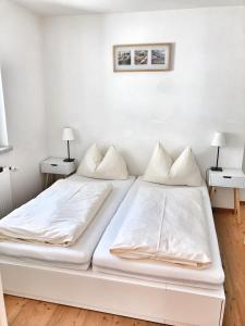 ein weißes Schlafzimmer mit 2 Betten und 2 Lampen in der Unterkunft Hubertus Dependance in Obertauern