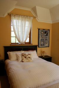 a bedroom with a white bed with a window at Appleby Guesthouse in Cape Town
