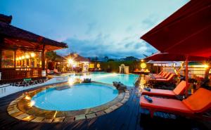 a swimming pool at night with chairs and umbrellas at Bali Taman Beach Resort & Spa Lovina in Lovina