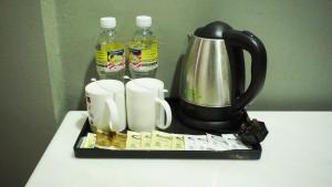 a tray with a tea kettle and two bottles of water at Langgura Baron Resort in Pantai Cenang