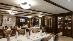 un restaurante con mesas y sillas blancas y TV en Hotel Herastrau, en Bucarest