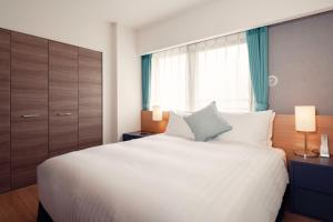 a bedroom with a large white bed and a window at Oakwood Apartments Nishi-Shinjuku in Tokyo