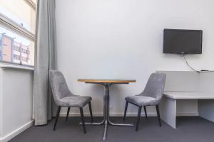 グレネルグにあるHi 5 Glenelg Studio Apartmentのテレビ付きの客室で、テーブルと椅子2脚が備わります。