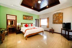 Bali Taman Beach Resort & Spa Lovina في لوفينا: غرفة نوم فيها سرير وتلفزيون