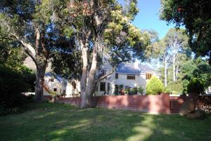 a white house with a brick fence and trees at Appleby Guesthouse in Cape Town