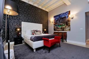 1 dormitorio con 1 cama grande y 1 silla roja en Sistina Twentythree luxury rooms, en Roma